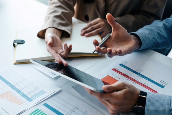 close up two business partnership coworkers discussing financial planning digital tablet paperwork